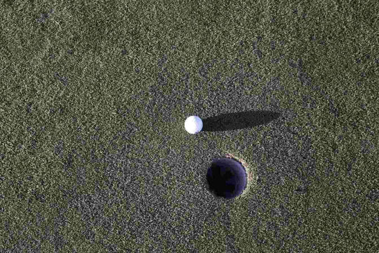 golf ball next to green on golf course 