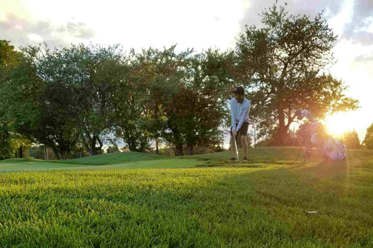man beside golf green about to hit chip shot